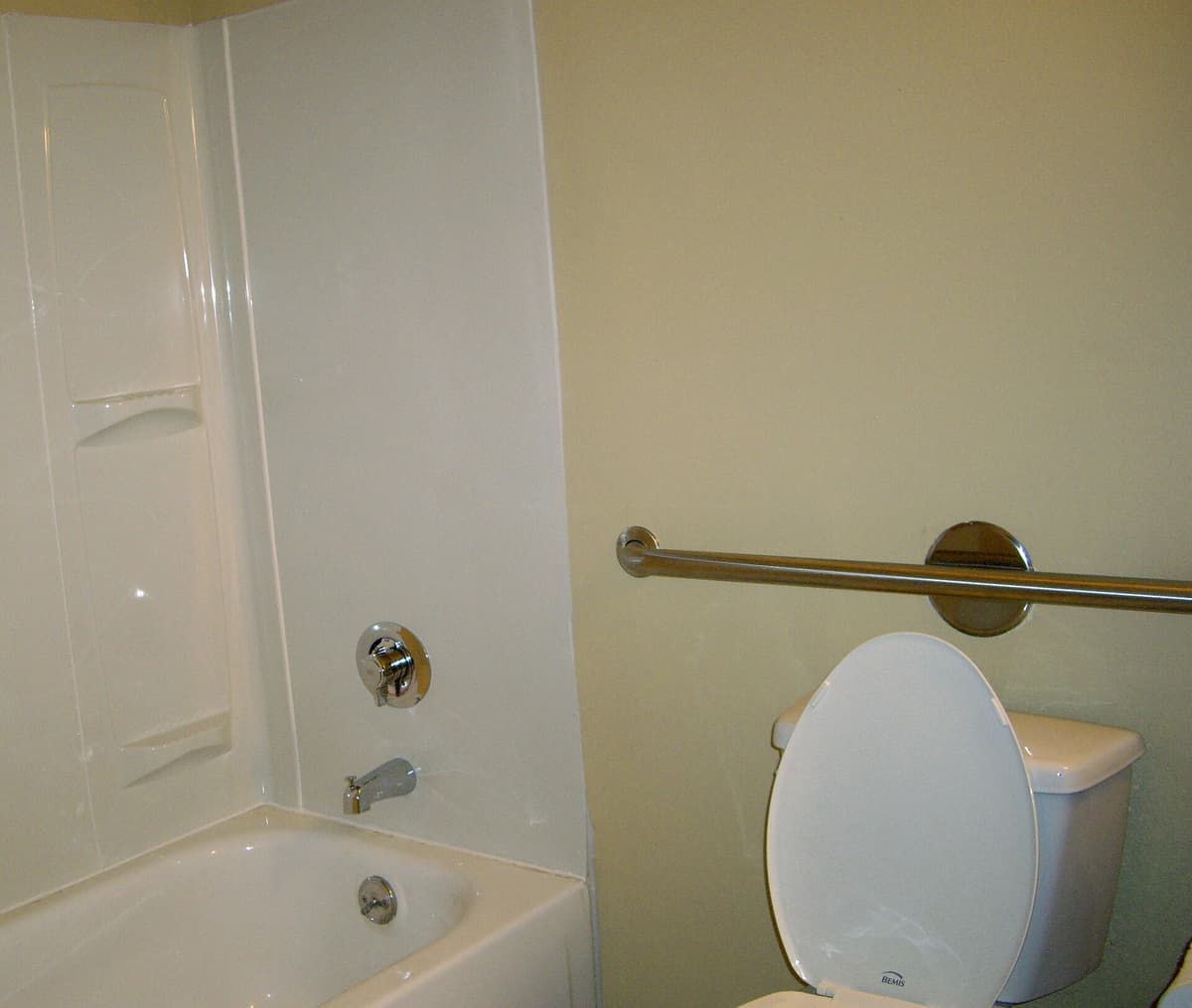 A stainless steel grab bar mounted on tiled bathroom walls
