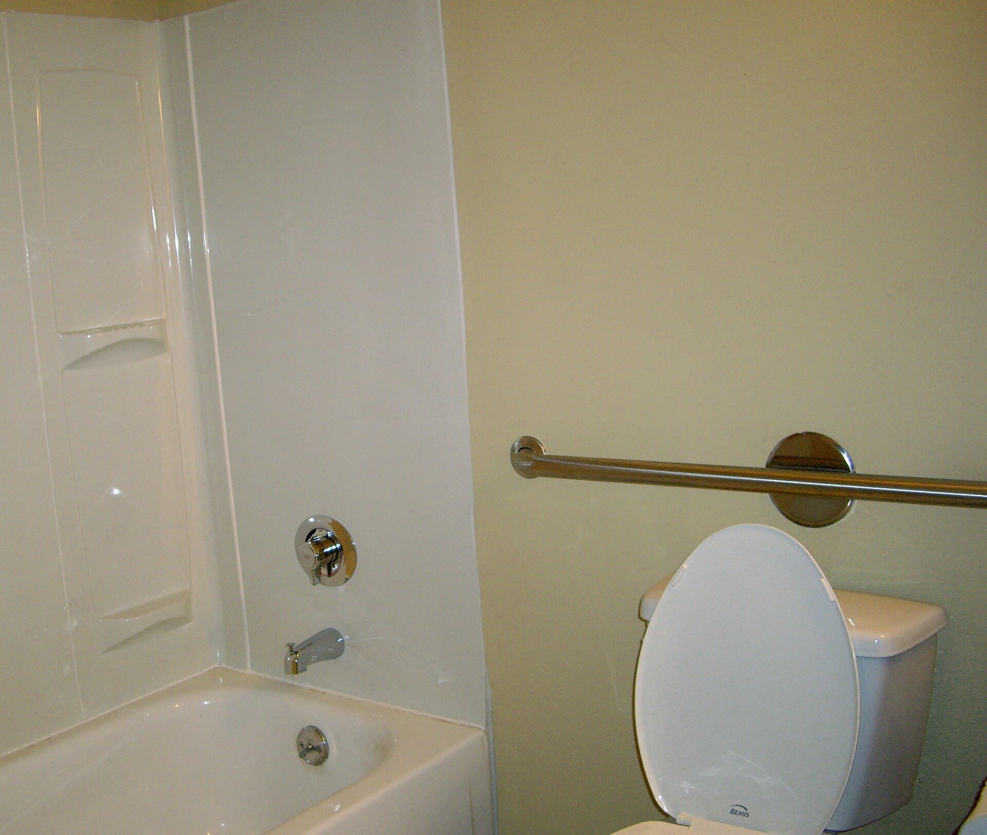A stainless steel grab bar mounted on tiled bathroom walls