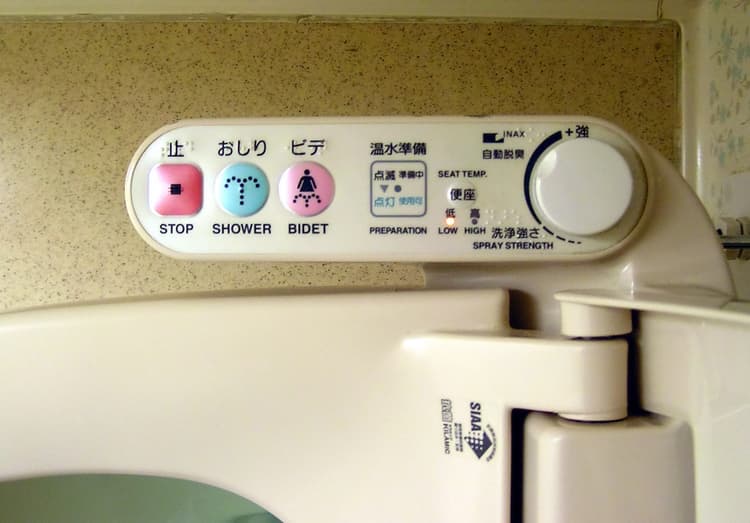 A modern Japanese toilet suite with an integrated washlet seat in a small bathroom