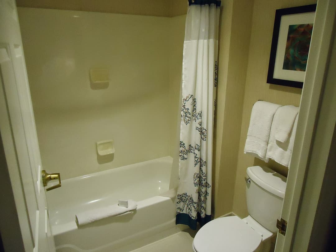 A hotel bathroom with towels near a shower and bathtub