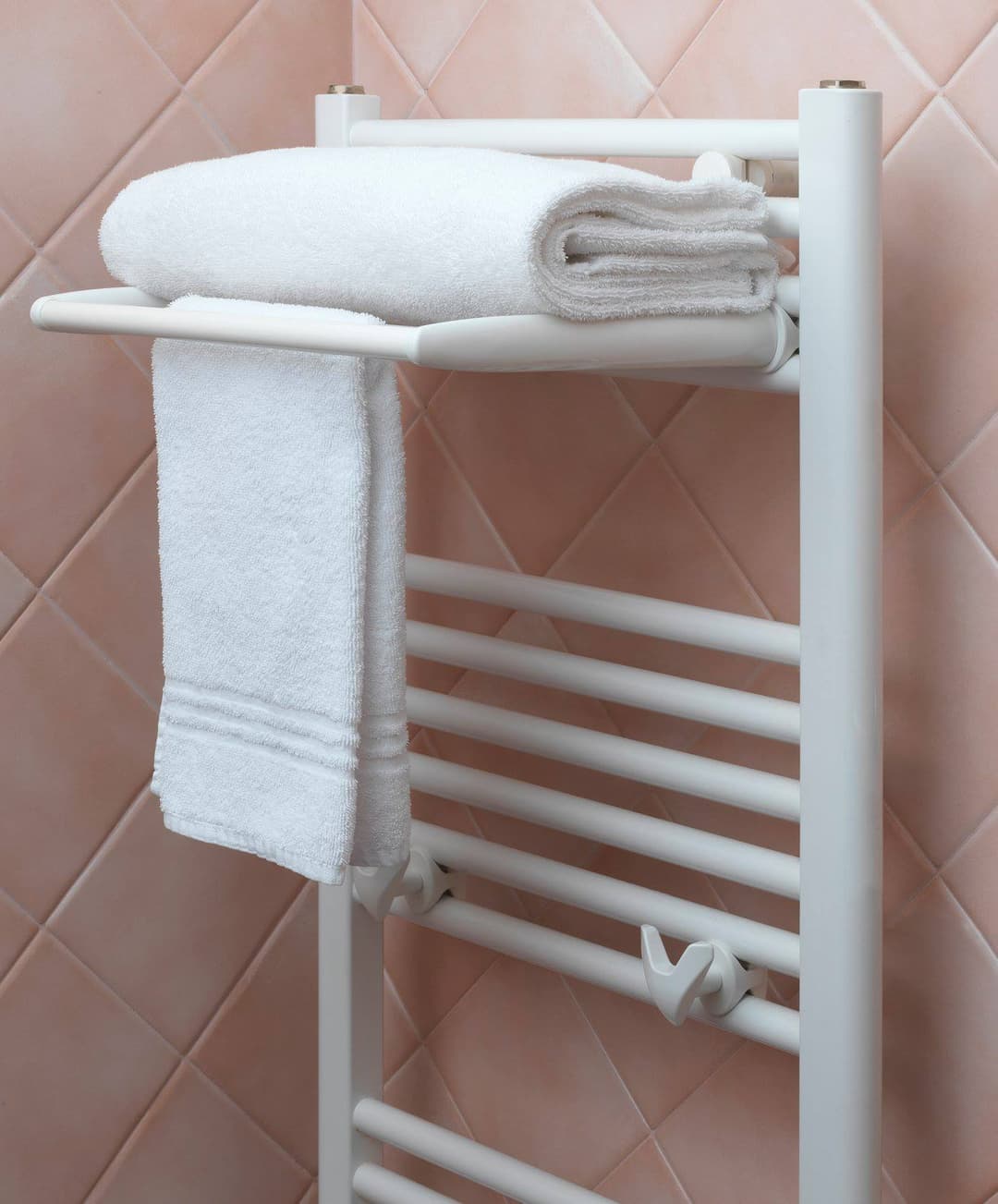 A heated towel rail with hanging bath towels in a bathroom