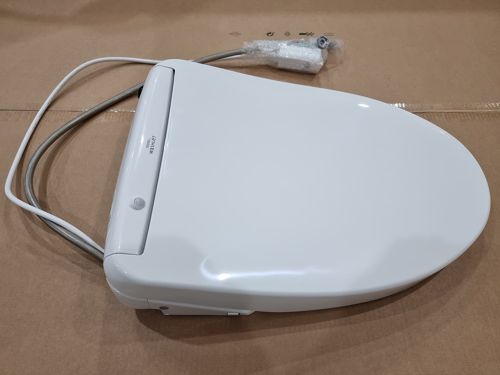 A white electronic bidet toilet seat installed on a ceramic pan, photographed from above